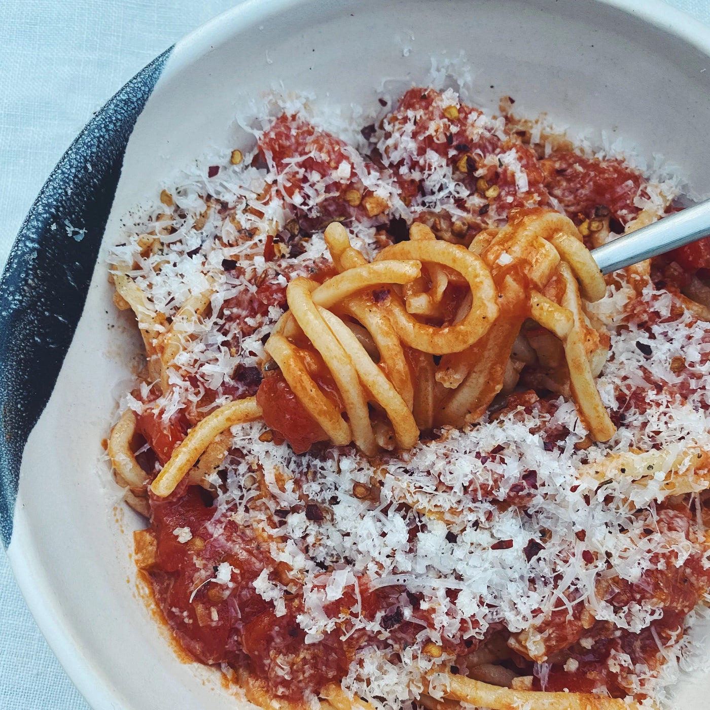 A bowl of pasta noodles with red sauce.
