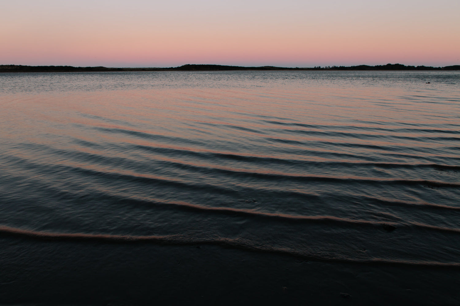 A sunset over the horizon of an ocean bay.