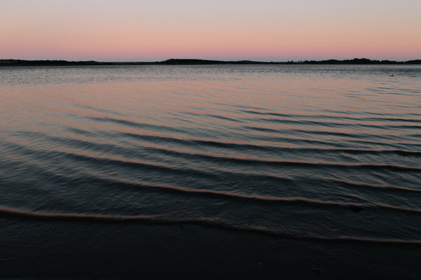 A sunset over the horizon of an ocean bay.
