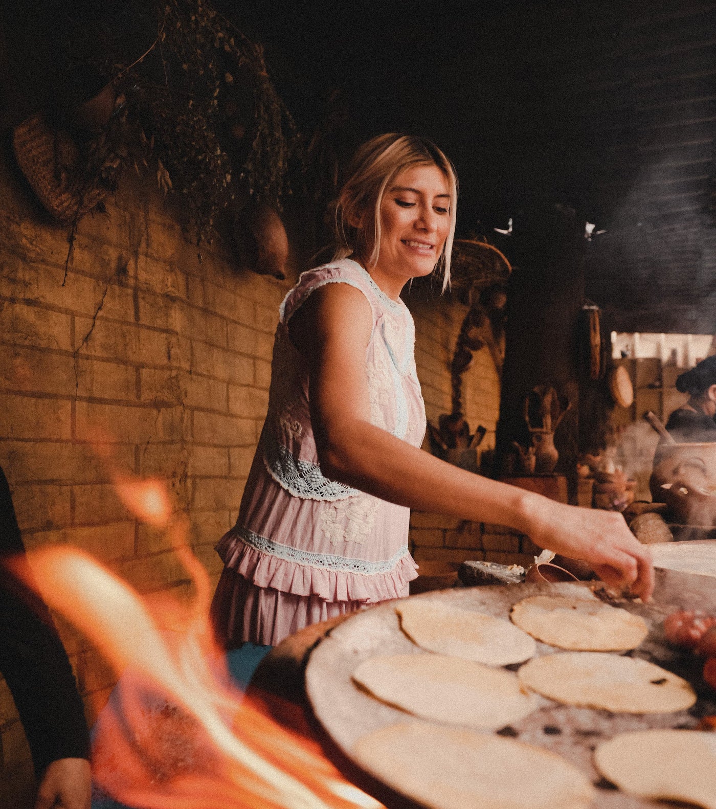A woman stands and smiles while cooking.