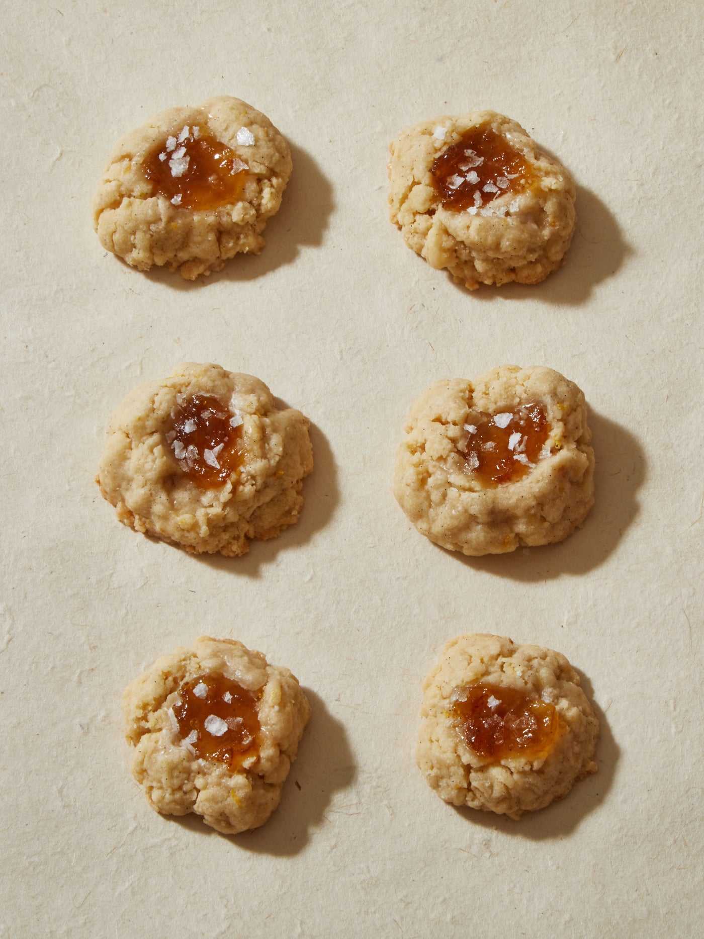 Six round tan cookies, with orange jelly and a pinch of flake salt in the middle.