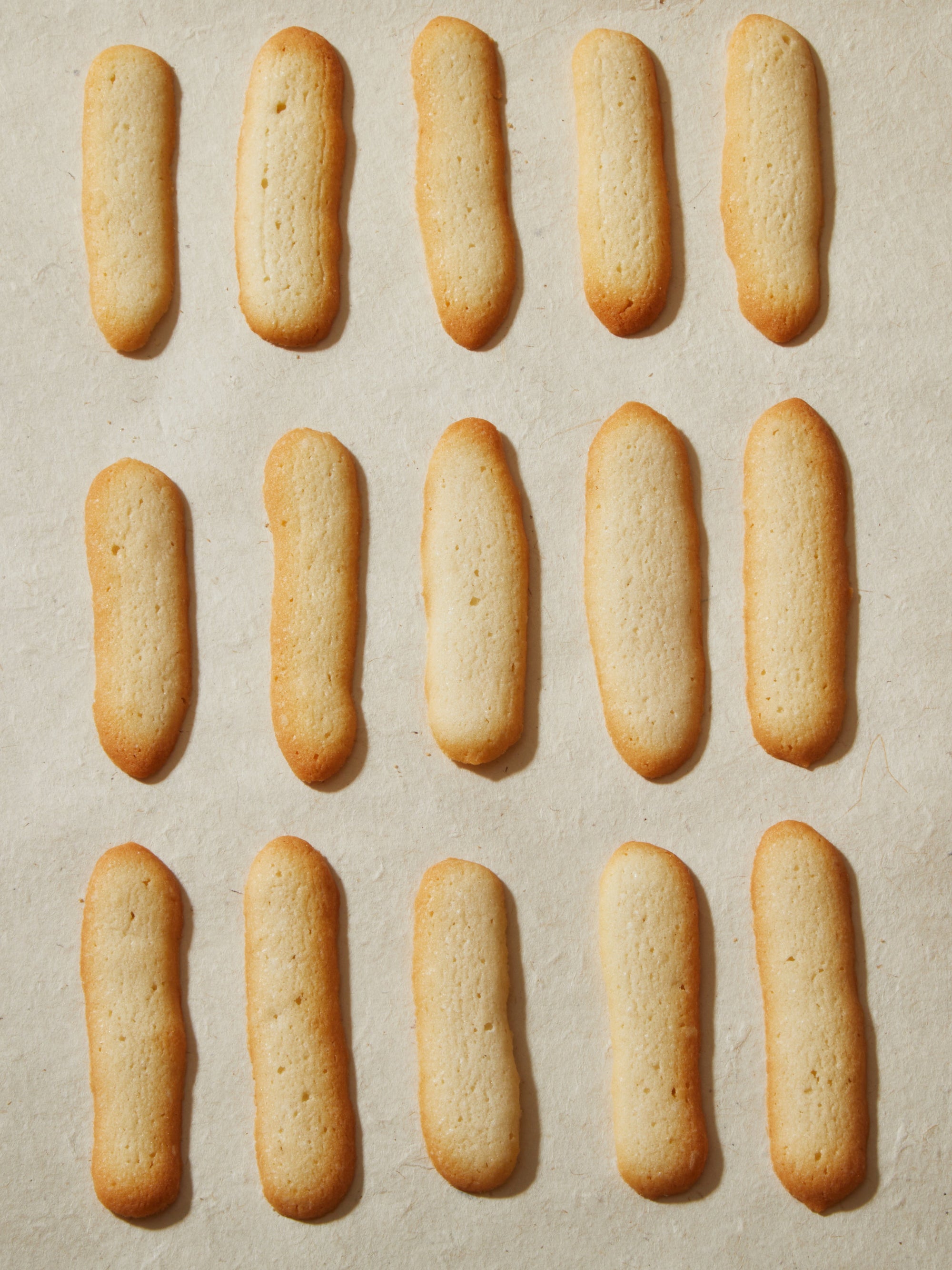 Fifteen long, tan colored cookies.