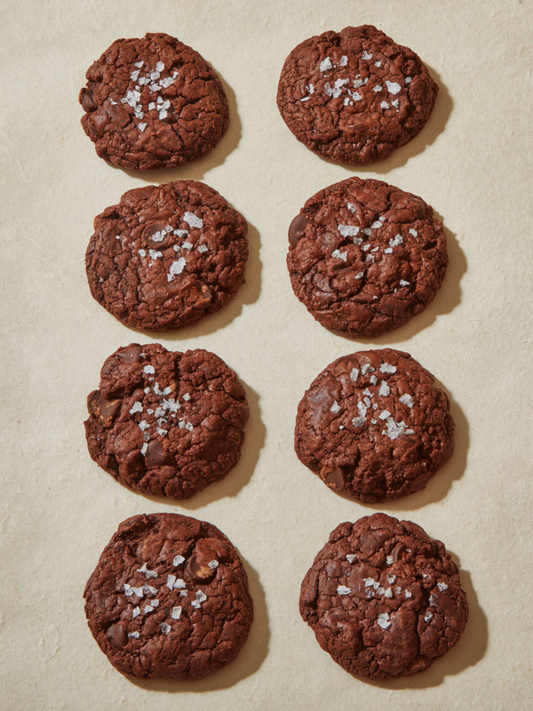 Eight dark brown circular cookies topped with flake salt.
