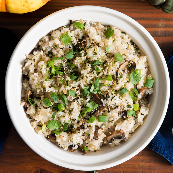 A bow of mushroom rice topped with chopped green onions and cilantro.