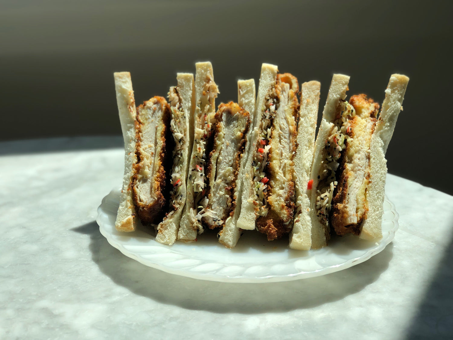 A plate with four chicken katsu sandwiches.