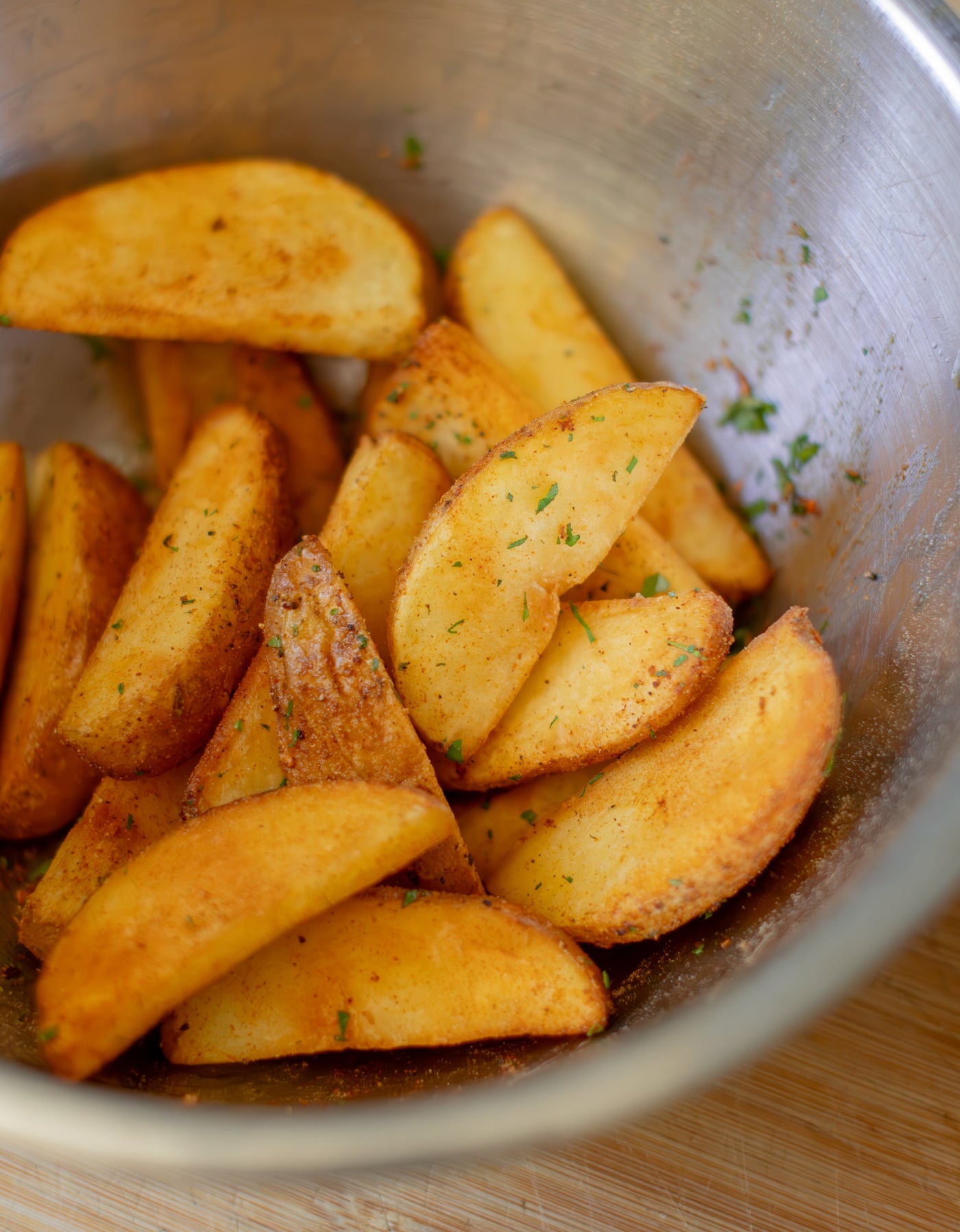 A bowl of fried potato wedges with seasoning.