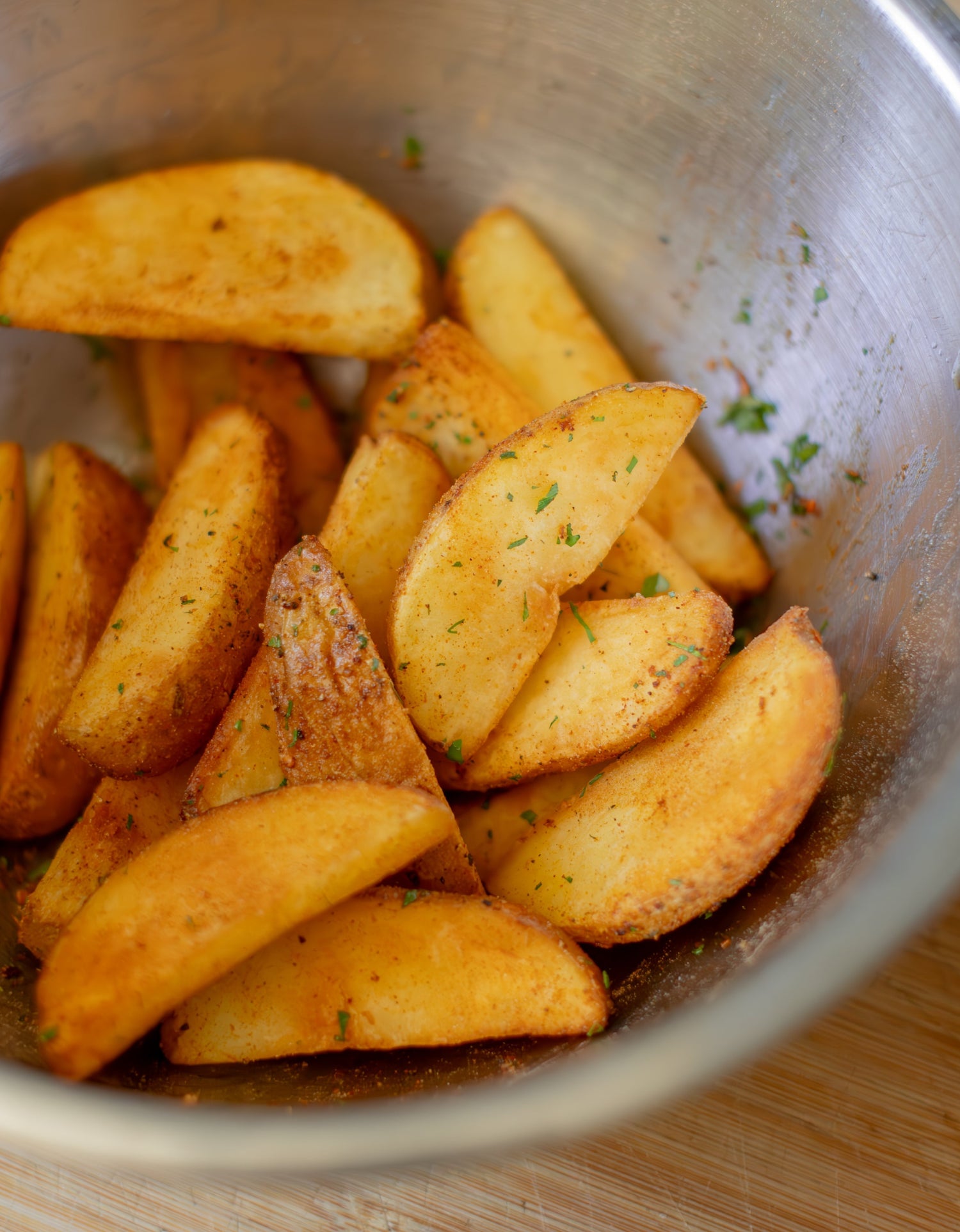 A bowl of fried potato wedges with seasoning.