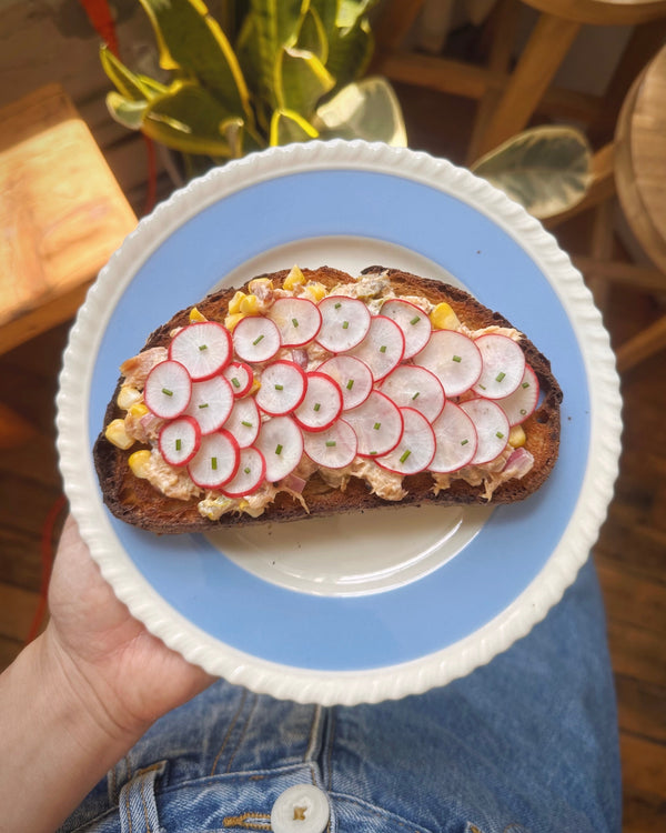 Toast topped with smoked salmon tartine and thin sliced radishes on decorative blue plate.