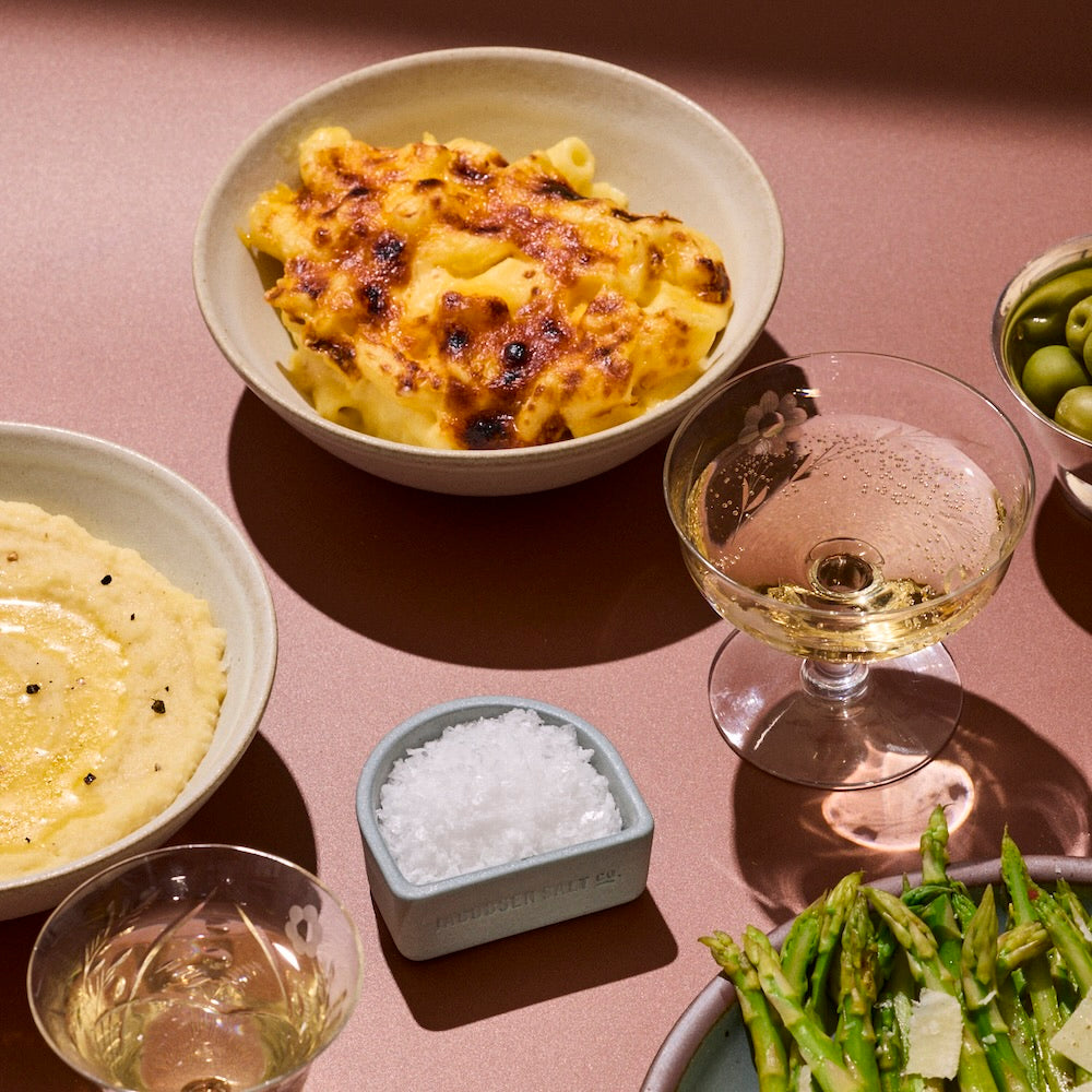 Various dishes of food and glasses of drinks on a burnt orange backdrop.