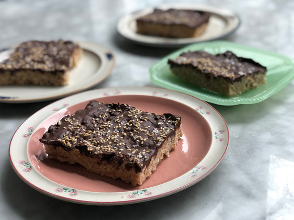 Four plates with slices of salty tahini rice crispy bars.