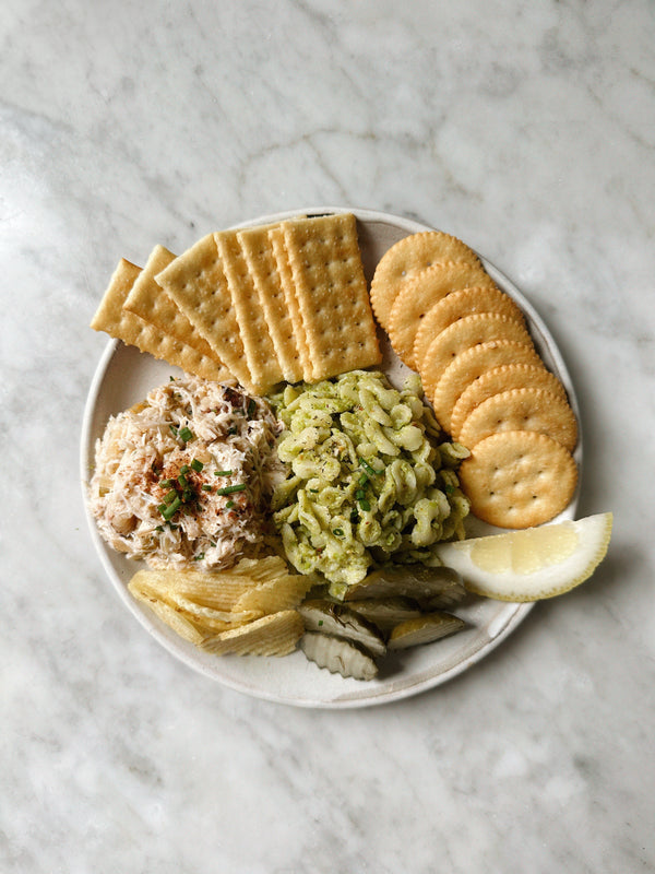 Plate with circular and rectangular crackers, next to various dips and toppings.