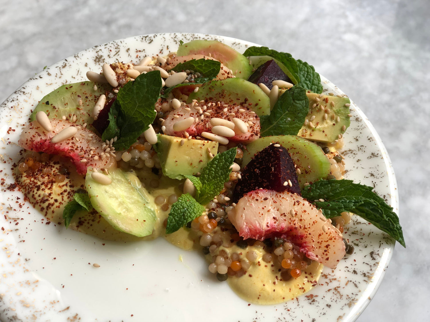 An avocado and peach salad on a white plate. 