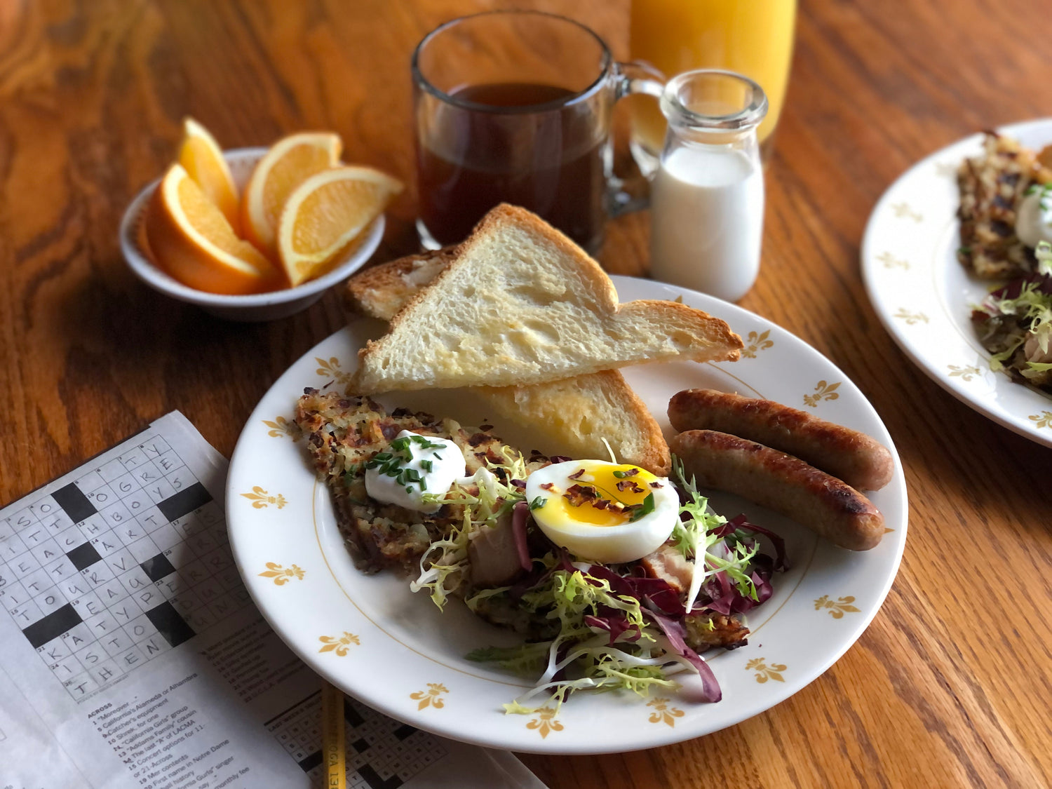 A breakfast spread and a newspaper on top of a wooden table.