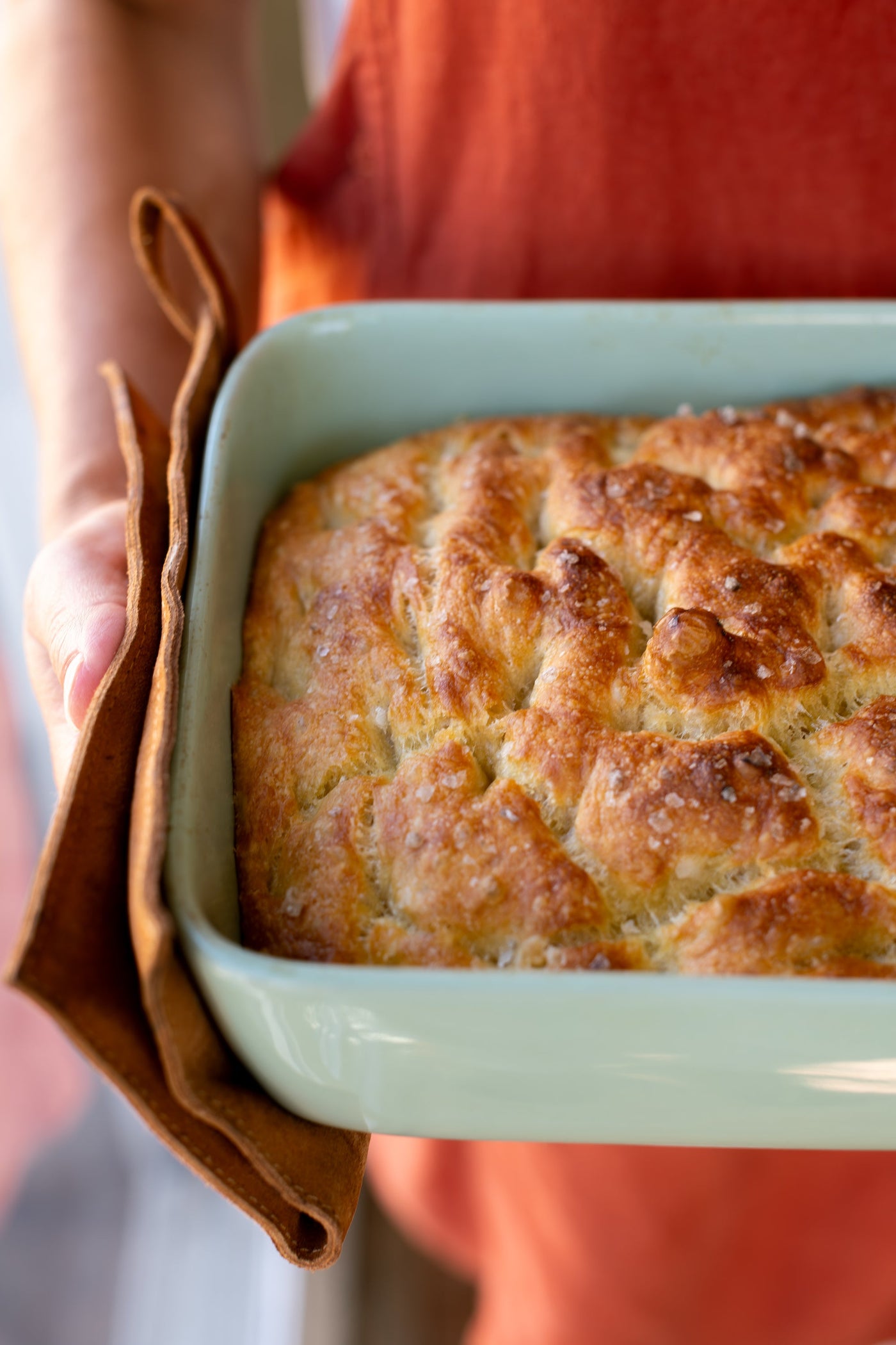 Closeup of freshly baked, unsliced focaccia in a serving dish.