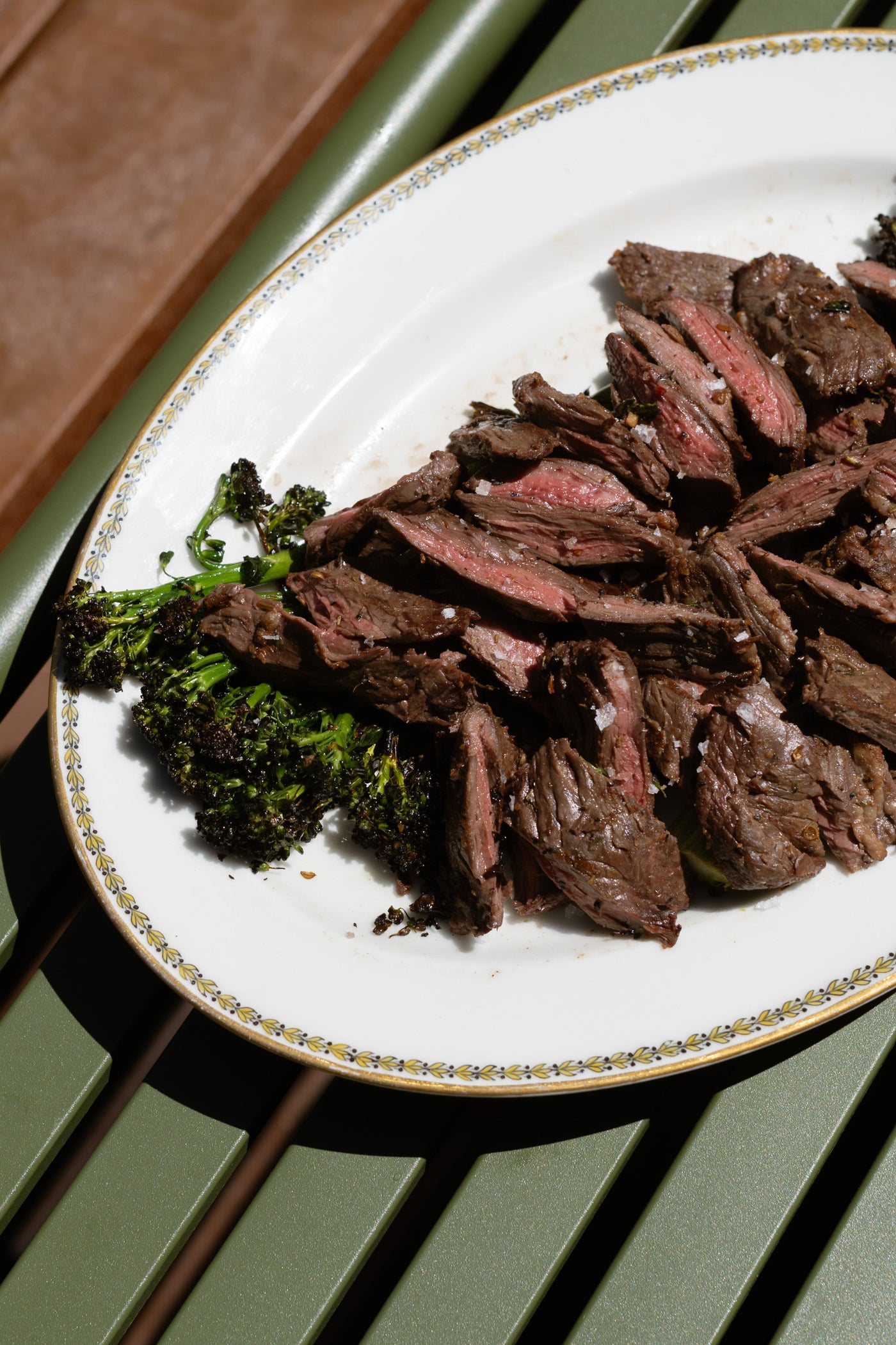 Sliced grilled steak, plated with broccoli. 