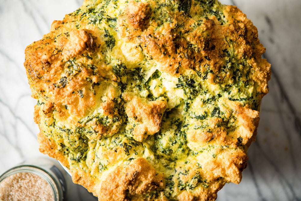 Closeup of golden brown soufflé, light and puffy with visible spinach.