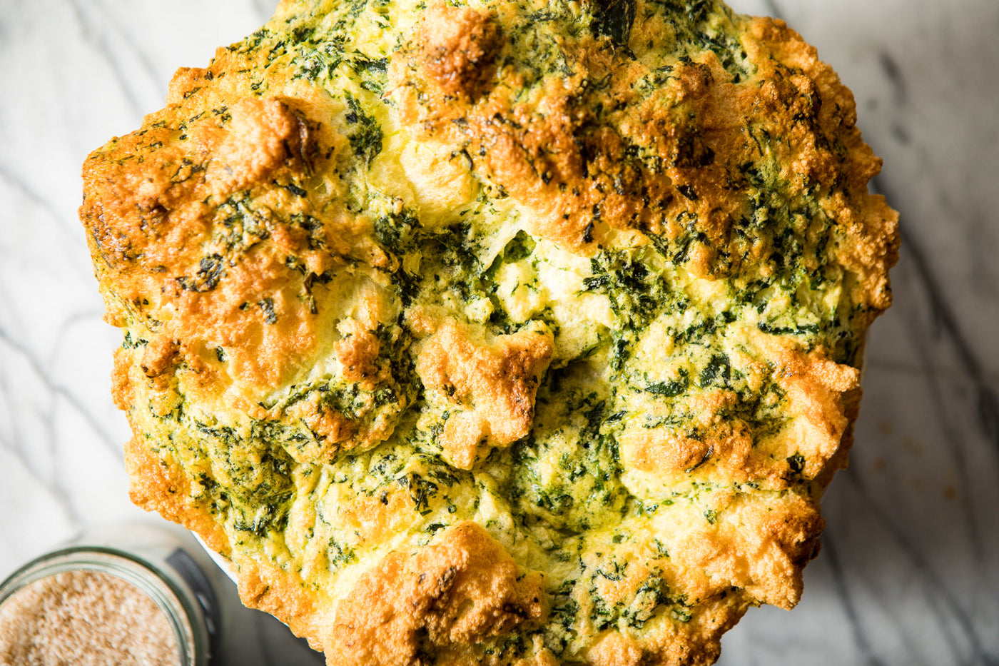 Closeup of golden brown soufflé, light and puffy with visible spinach.