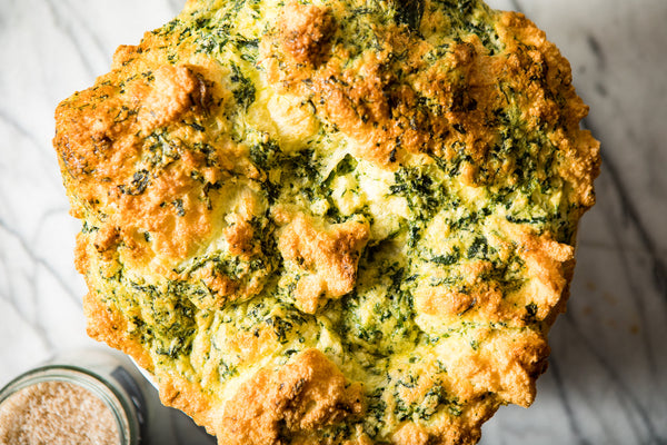 Closeup of golden brown soufflé, light and puffy with visible spinach.