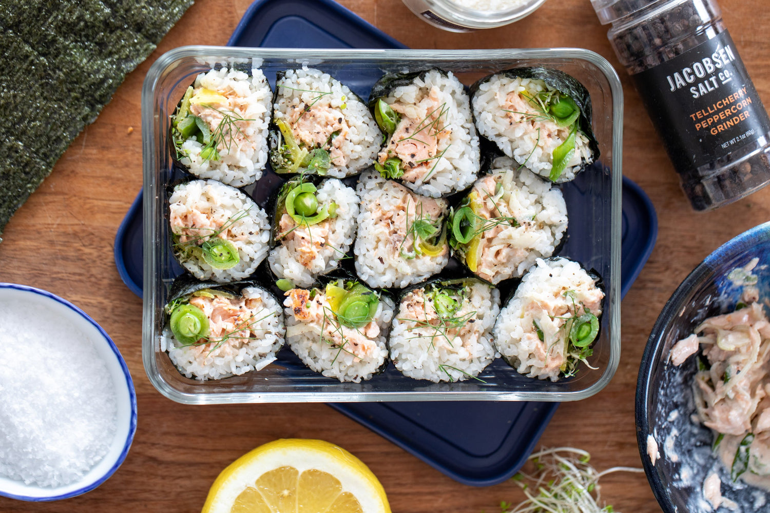 A glass Tupperware filled with slices of salmon kimbap.