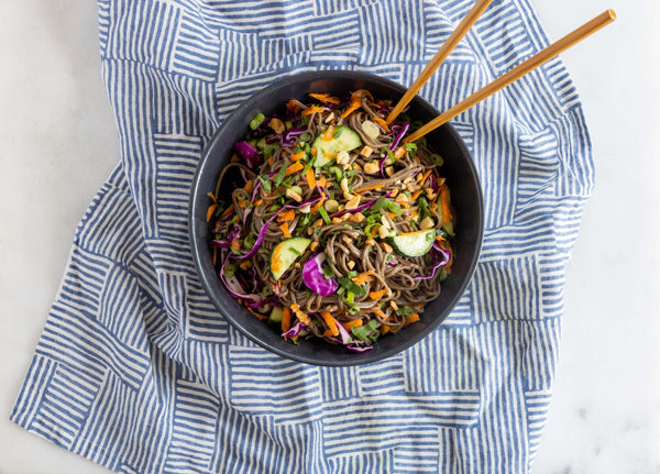 A bowl of soba noodle salad on a kitchen towel.