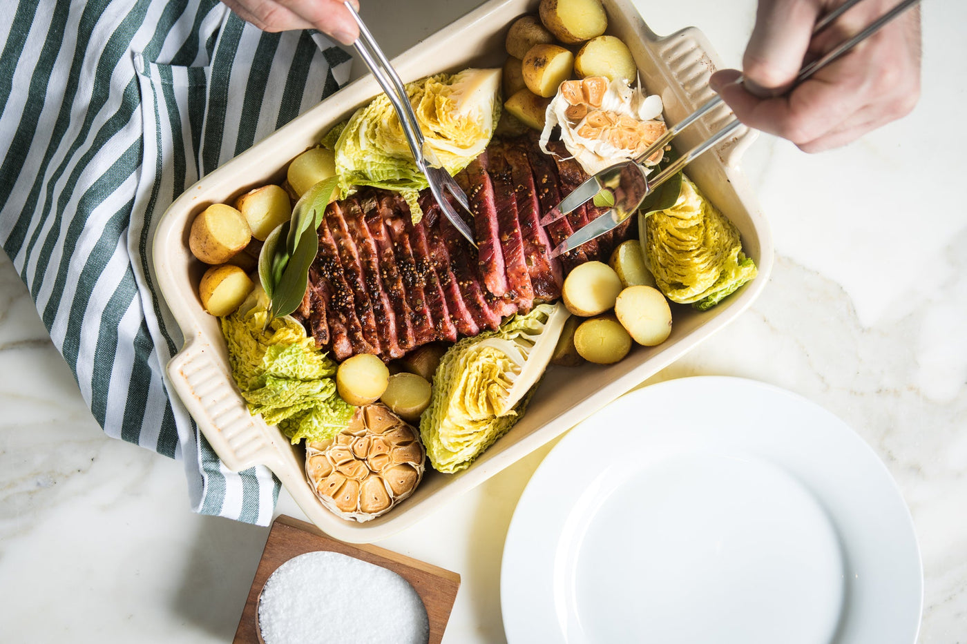 A white baking pan filed with corned beef, cabbage and potatoes.