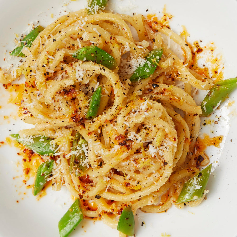 A bowl of spaghetti noodles and snap peas.