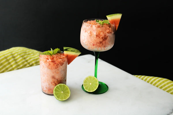 Two glasses of watermelon granita on top of a white table.