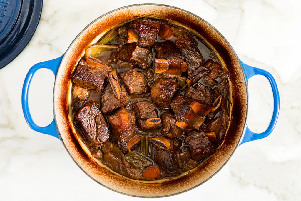 A bowl of dark brown braised beef, cut into pieces.