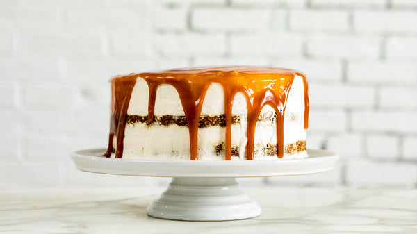 A white frosted cake topped with dark brown Buckwheat Honey, dripping over the sides.