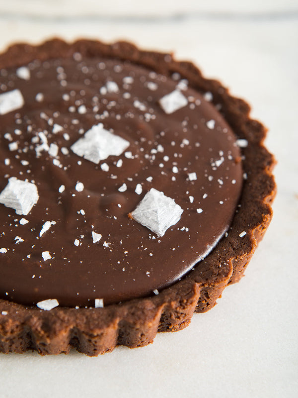 Dark brown, circular peanut butter tart, with very large salt flakes on top.