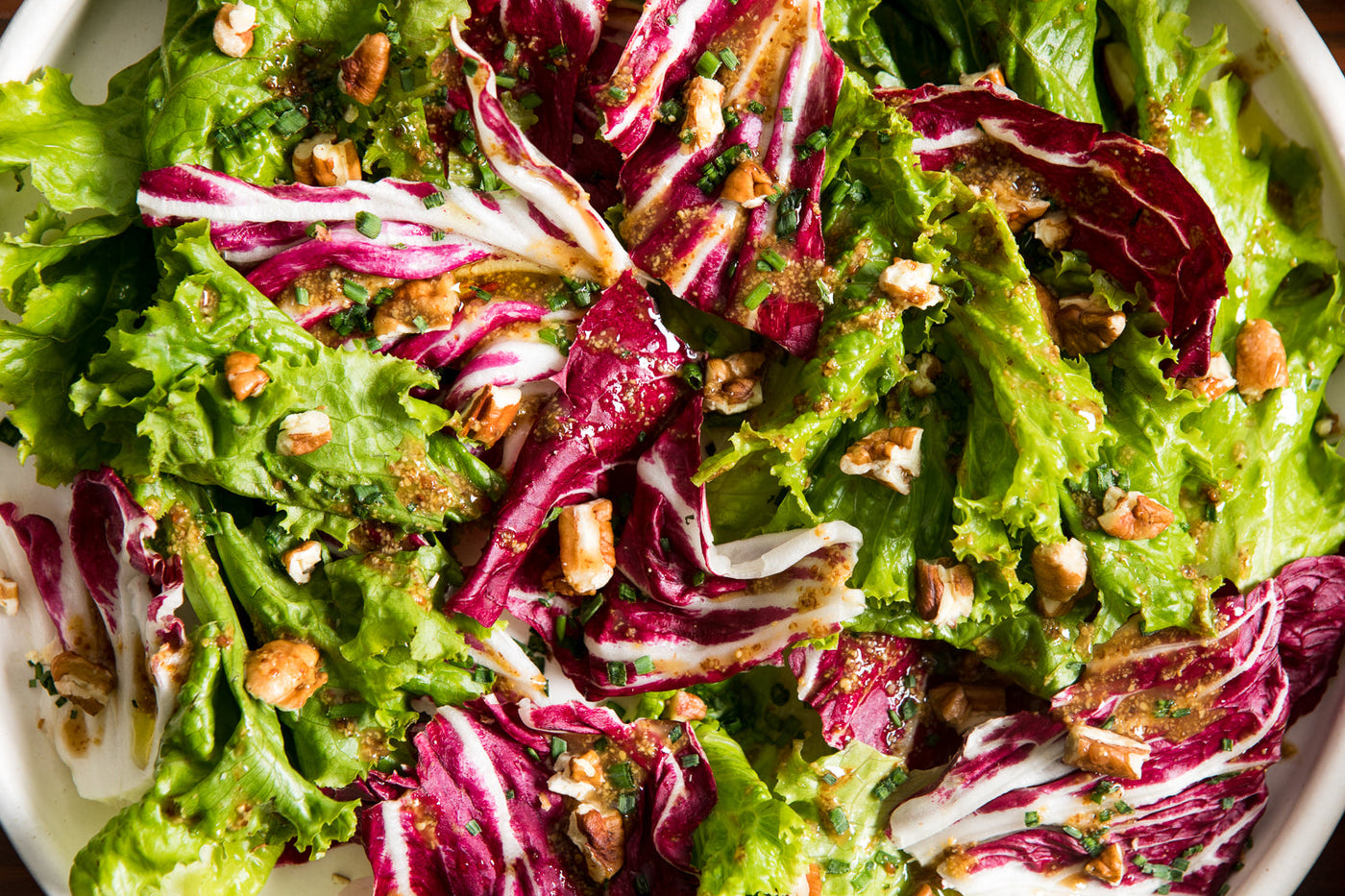 A bowl of chicory salad with a honey mustard dressing.