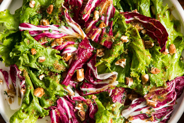 A bowl of chicory salad with a honey mustard dressing.