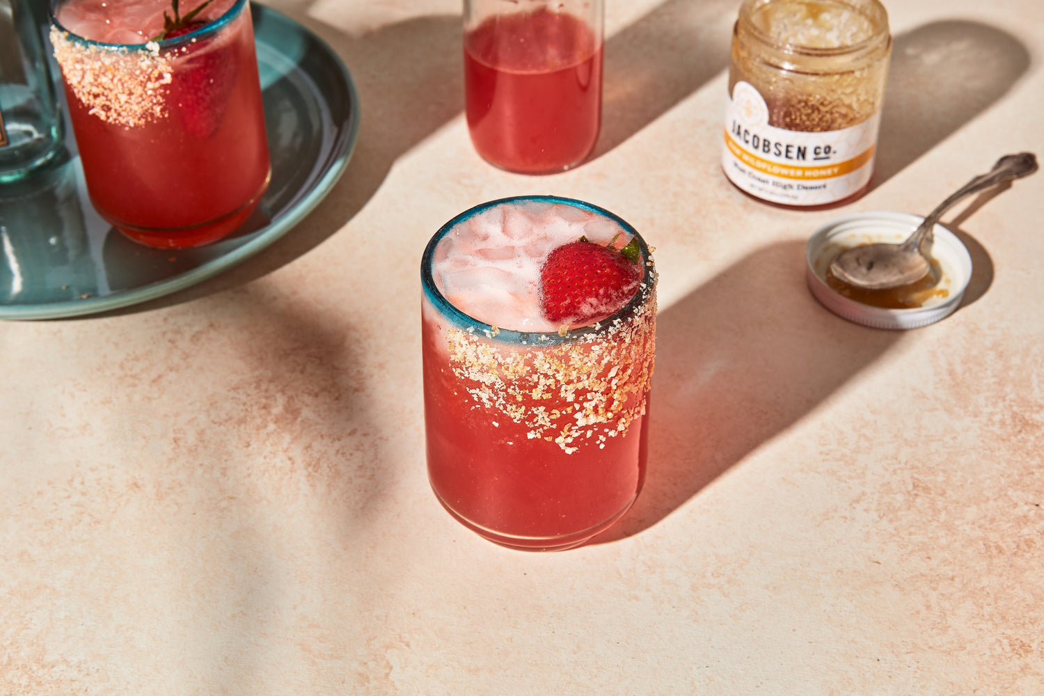 A glass of strawberry shrub beverage garnished with a fresh strawberry.