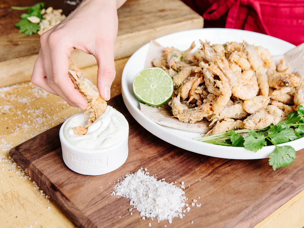 Plate of deep fried shrimp, being dipped in aioli sauce