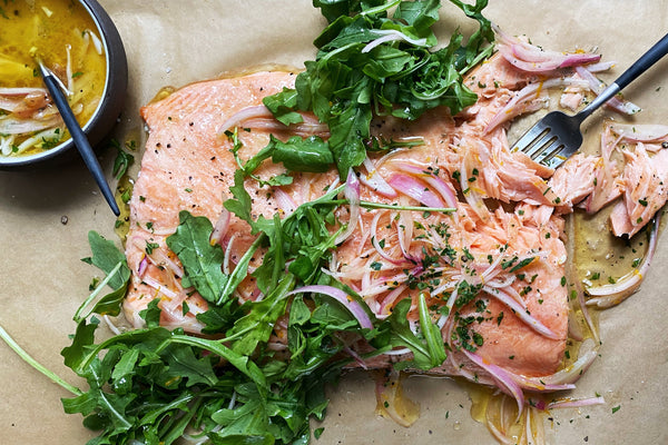 Roasted salmon and arugula on a piece of parchment paper.