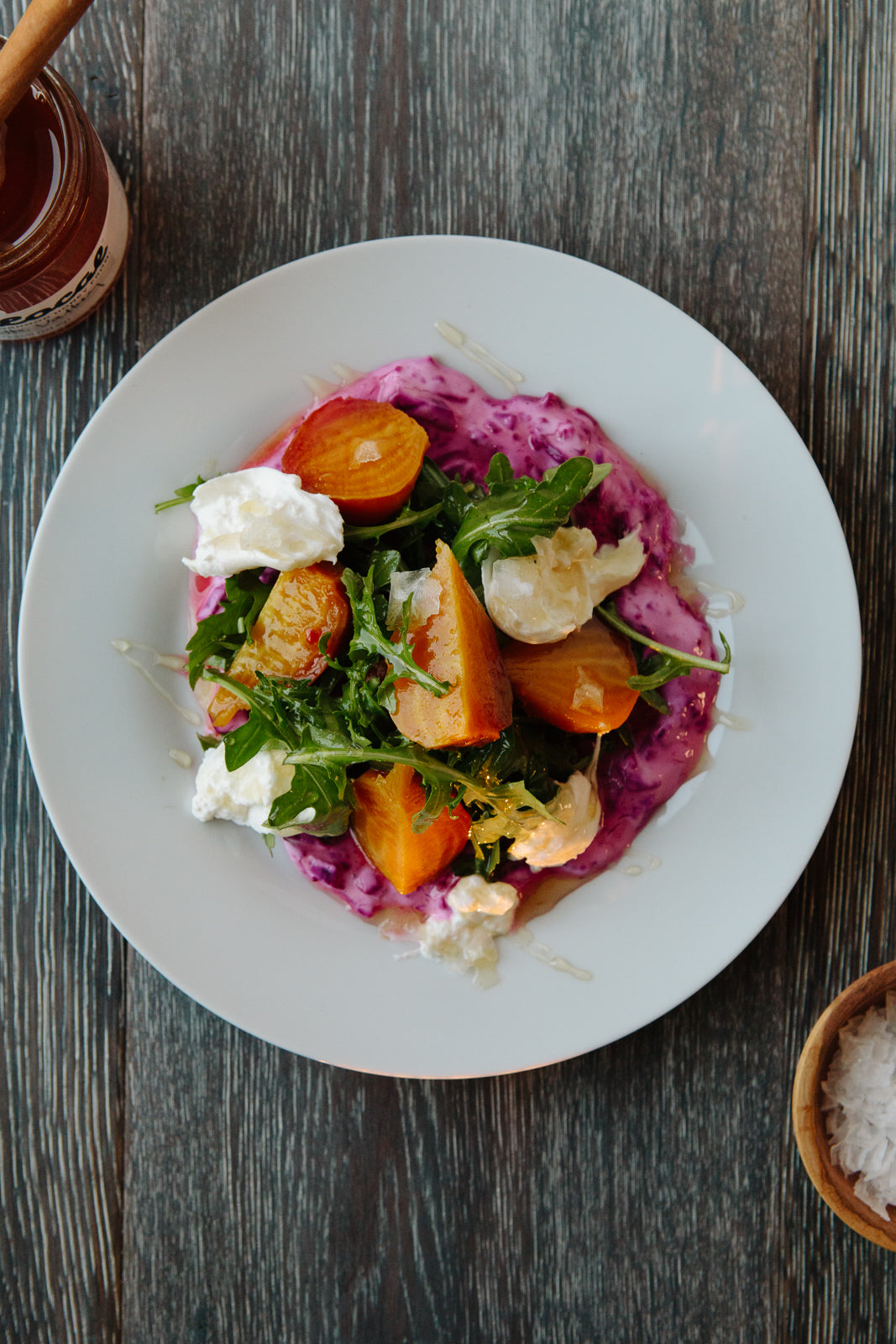 Colorful plate of food, including beet yogurt sauce, carrots, burrata and greens