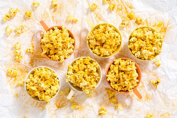 Six small bowls of golden popcorn.