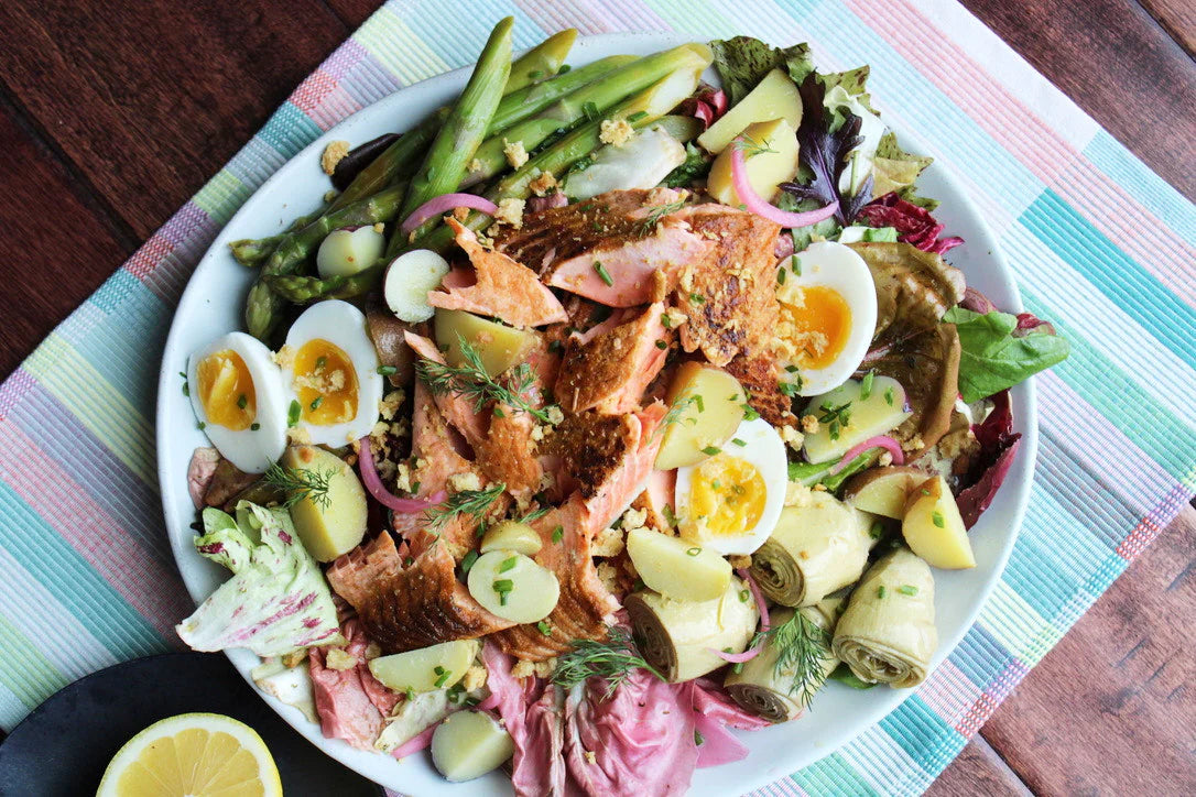 A variation of a Niçoise salad with salmon on a plate.