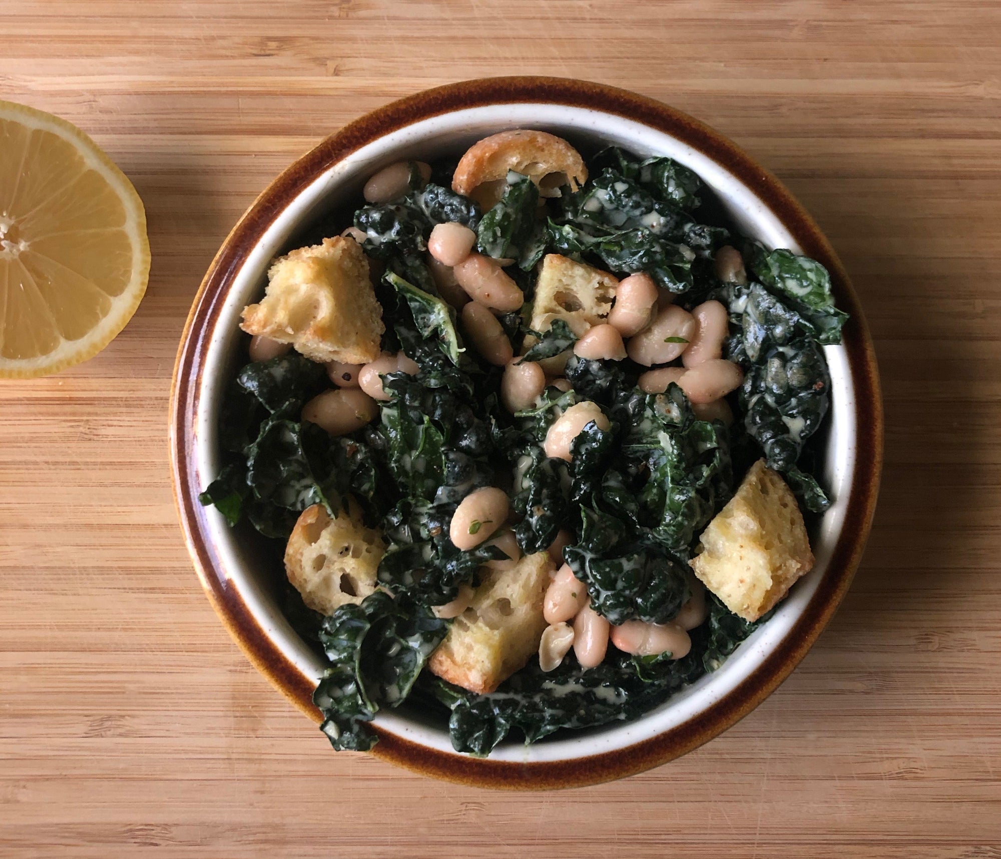 A bowl of mixed kale, beans, and croutons.