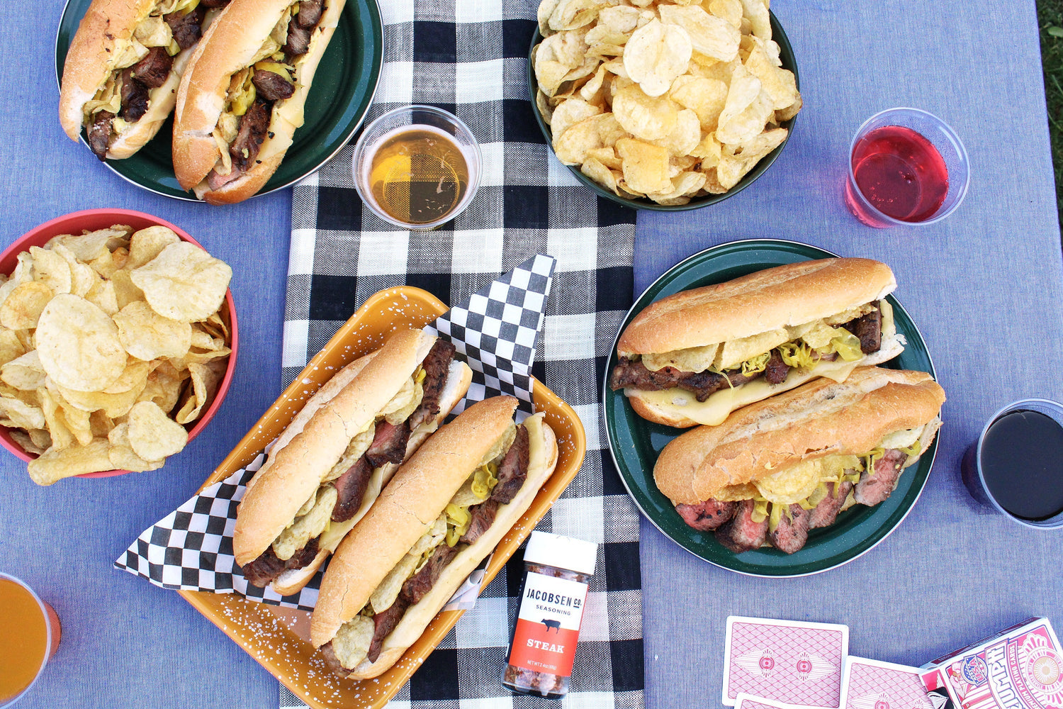 Several plates of french dip sandwiches and chips.