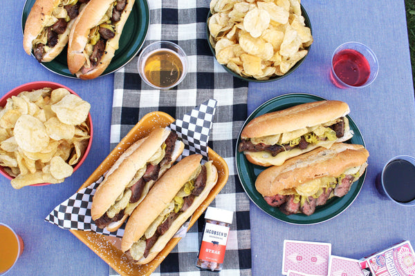 Several plates of french dip sandwiches and chips.