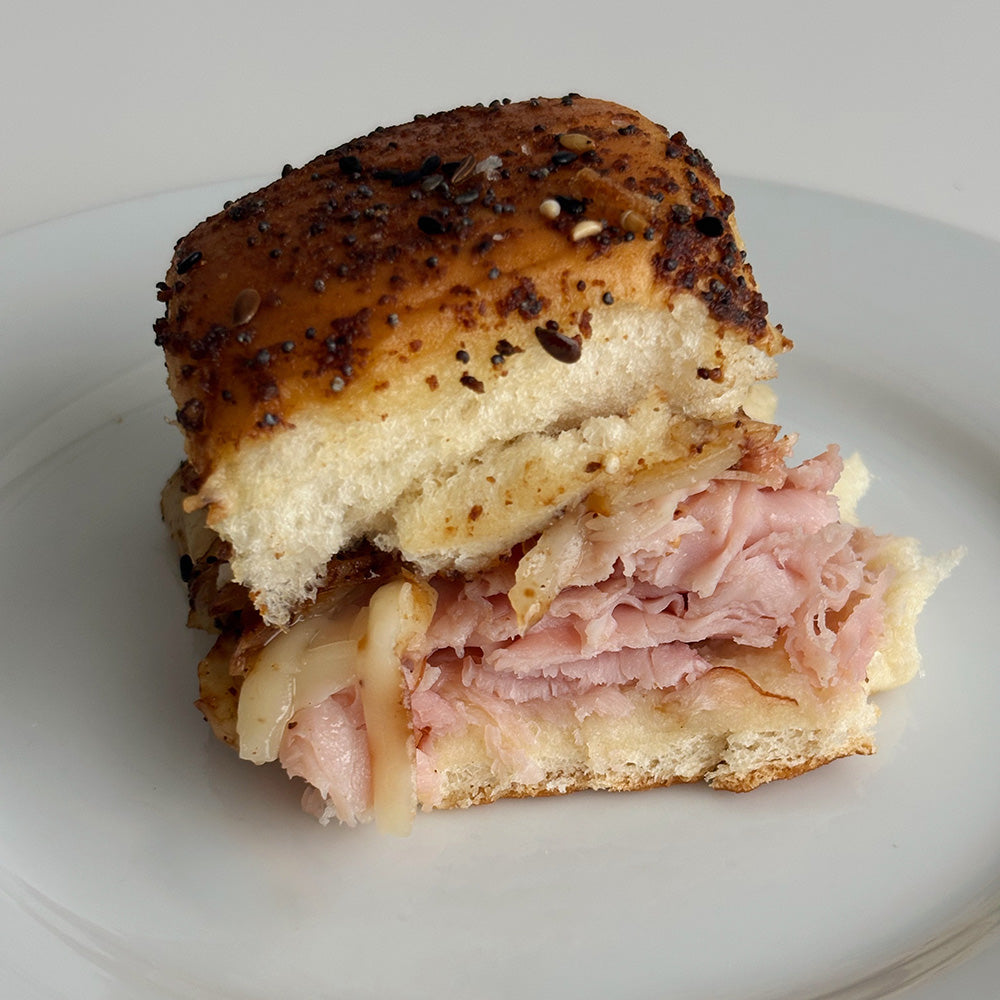 A roll filled with ham and cheese, topped with seasonings.