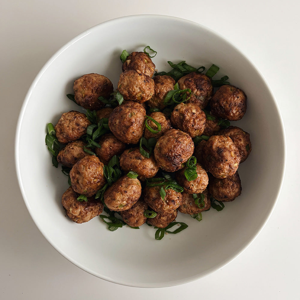 A white bowl filled with meatballs.