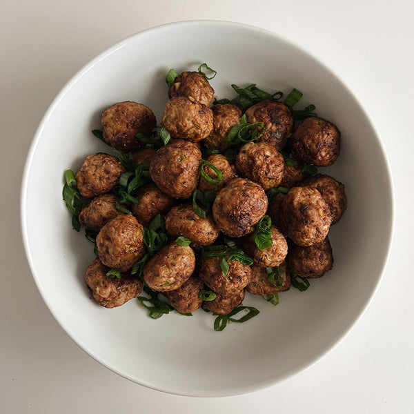 A white bowl filled with meatballs.