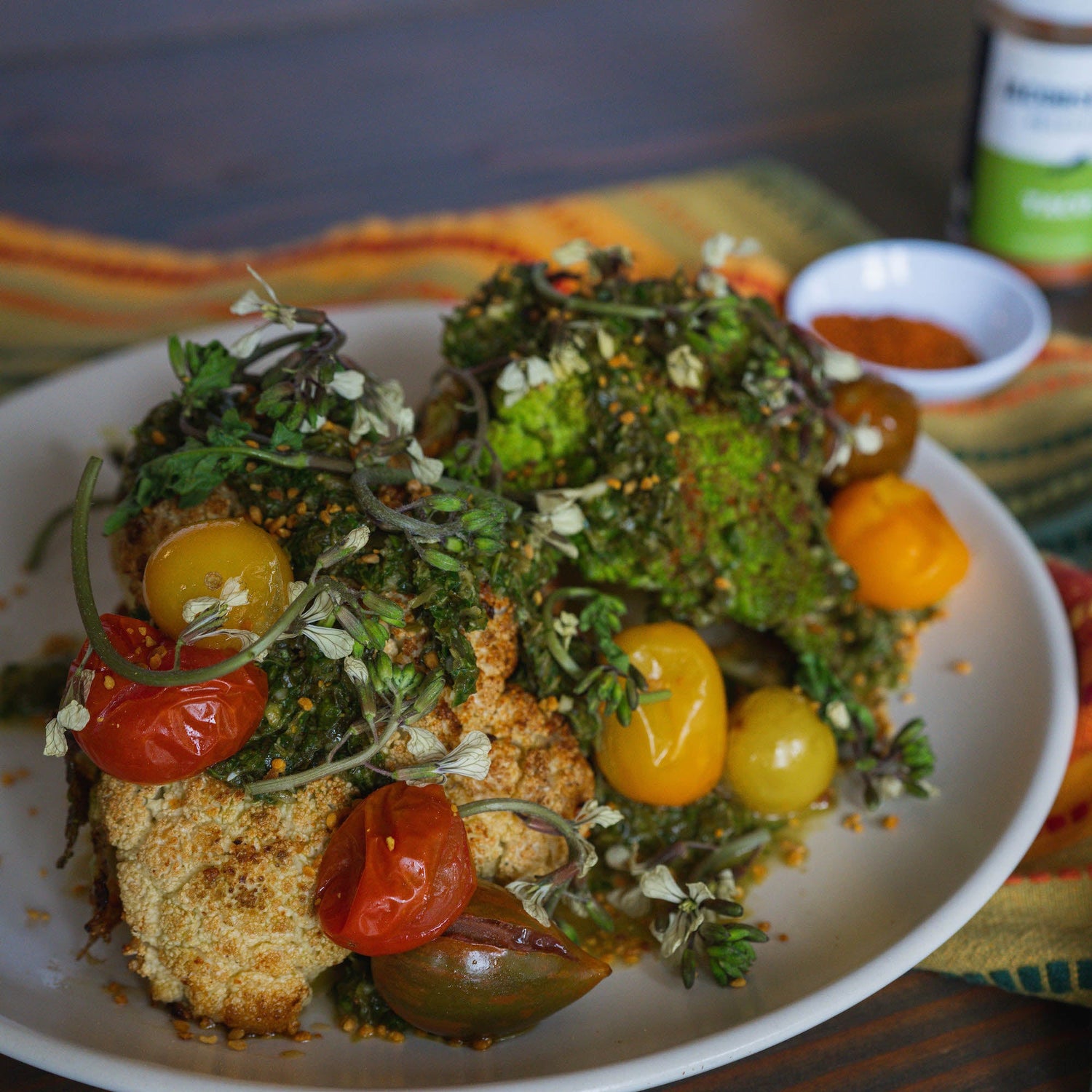 A plate with cauliflowers, greens, and cherry tomatoes. 