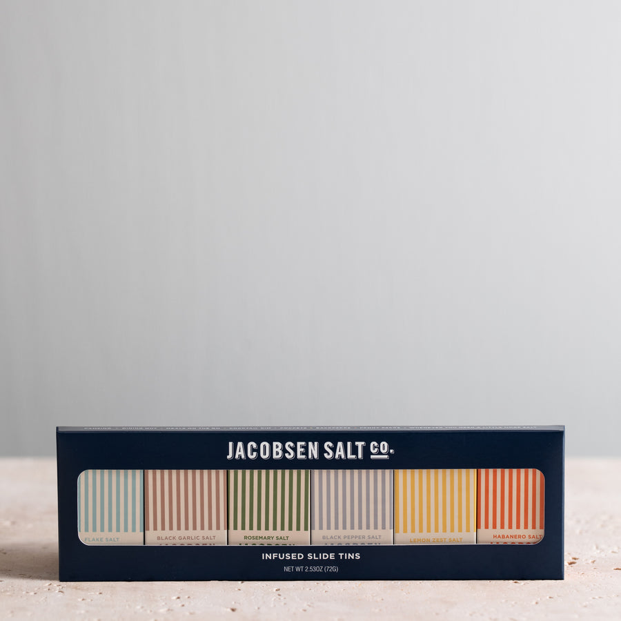 Six Infused Sea Salt slide tins of various flavors, packaged in a gift box