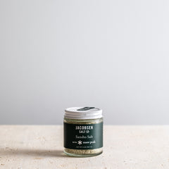 Jar of Jacobsen Salt Co. Sansho Salt on a light surface with a gray background