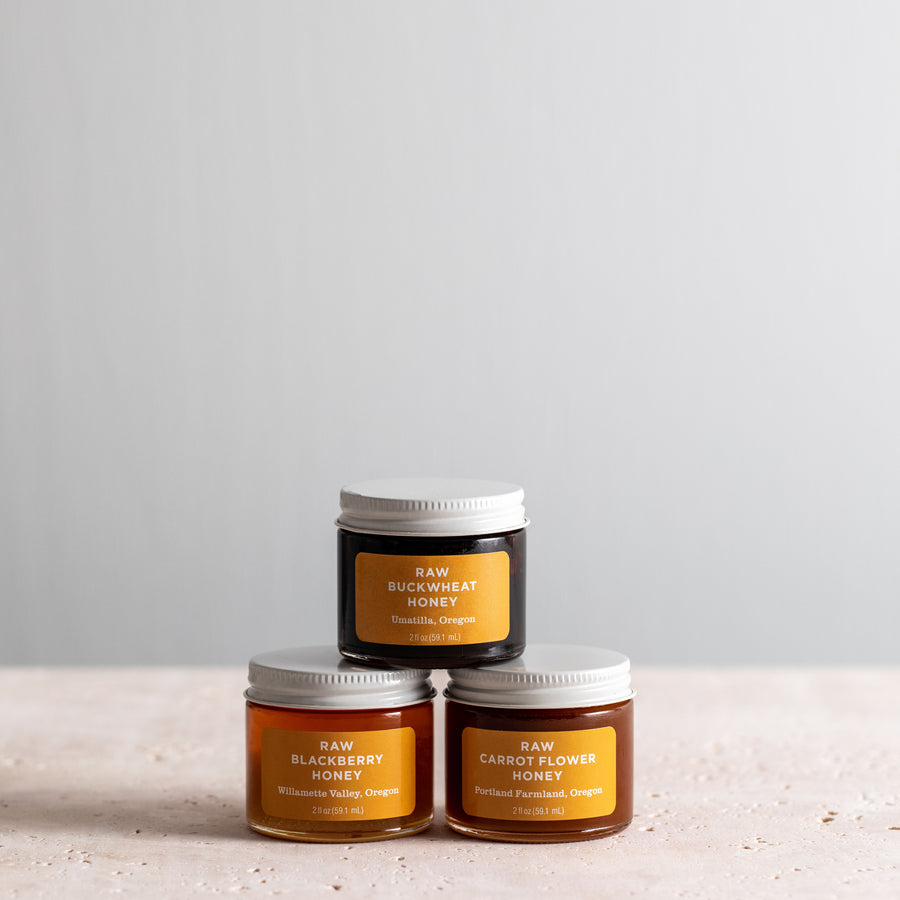 Three mini jars of Jacobsen Raw Honey, including Raw Blackberry Honey, Raw Buckwheat Honey and Raw Carrot Flower Honey