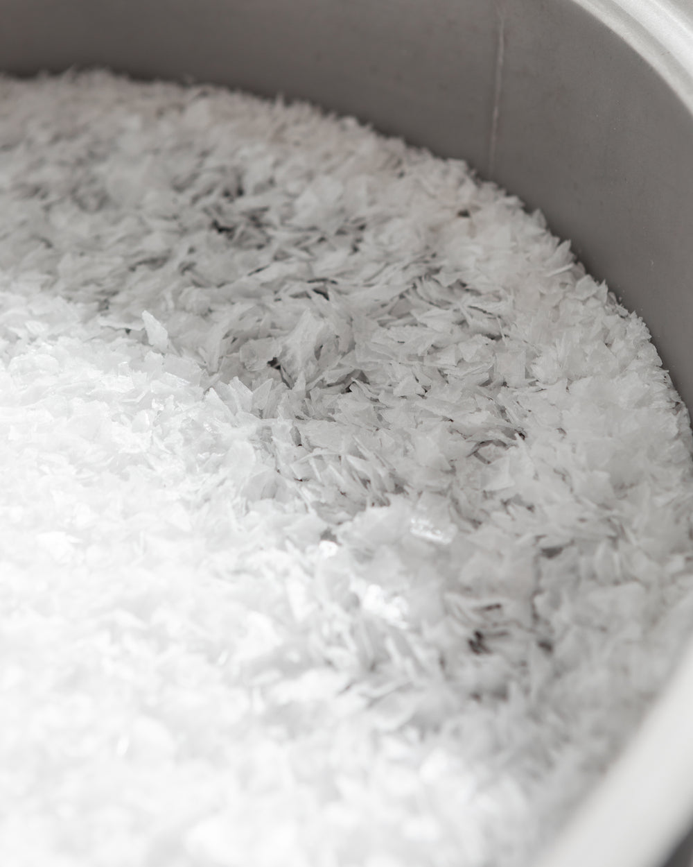 A large pile of flake salt in a grey bowl. 