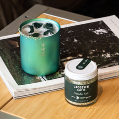 Green drink in a glass with a Jacobsen Salt Co. Sansho Salt container on a wooden surface.